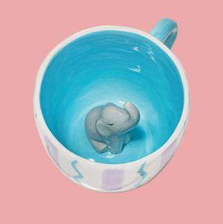 Blue mug with a small elephant figurine inside on a white background